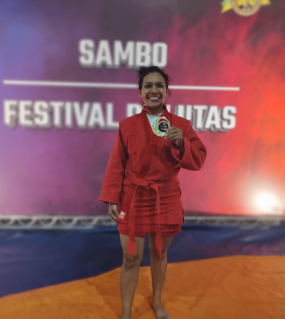 Polyana Campos, de quimono vermelho, mostra a medalha no Festival de Lutas do Arnold Classic 2023