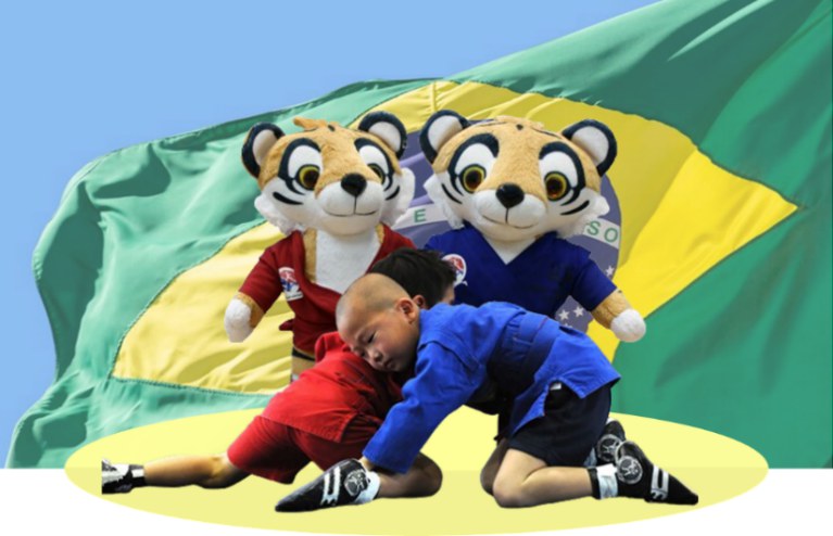 Crianças praticando SAMBO com mascotes tigres diante da bandeira do Brasil