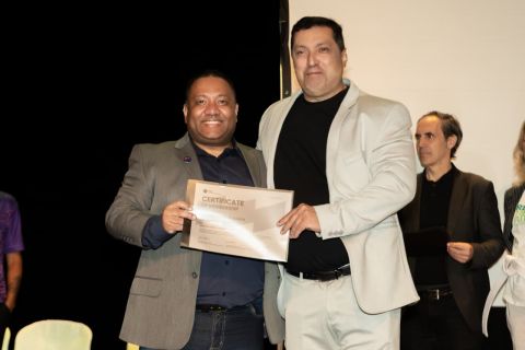 Dois homens seguram juntos, em um palco, o certificado de membro (Certificate of Membership) da coalizão