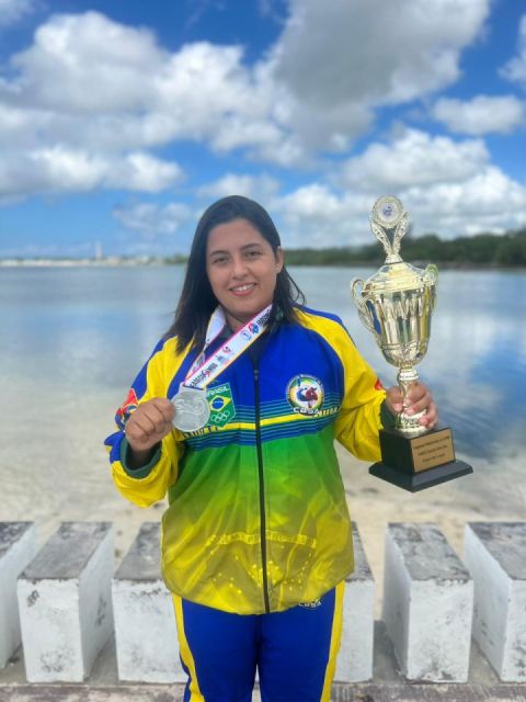 Jhenifer Silva, de agasalho da seleção, mostra a medalha e o troféu do Pan-Americano 2023