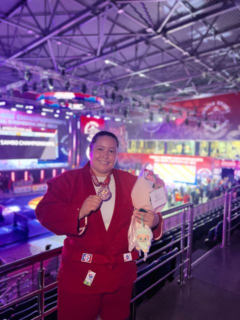 Priscila Rodrigues de Souza, de quimono vermelho, mostra a medalha de bronze na arena do Mundial