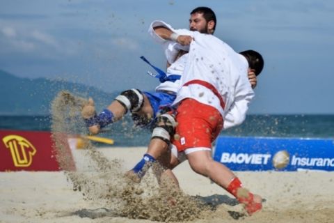 Luta de SAMBO de praia na areia, com um atleta projetando o outro à beira-mar
